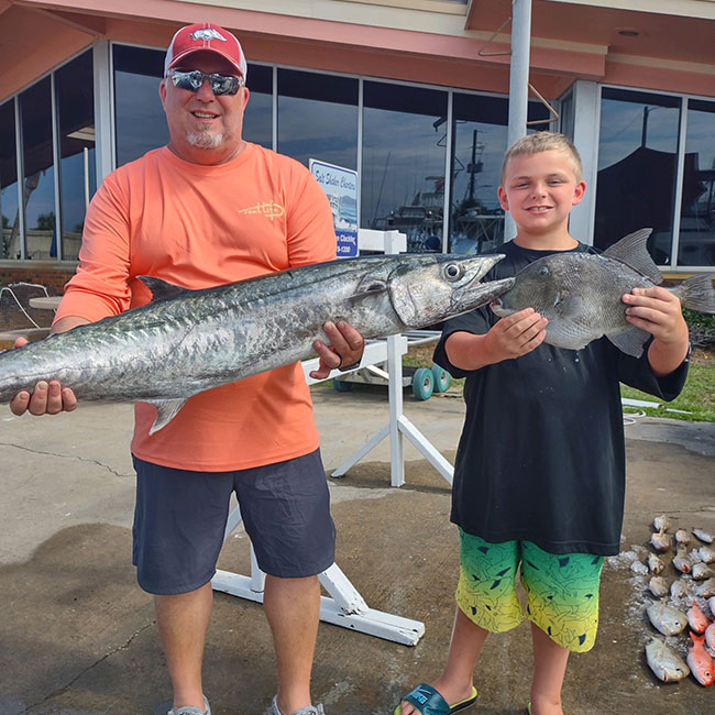 Father and son with their catch on the Panama City Beach dock after a successful Saltshaker Charters fishing trip in Florida