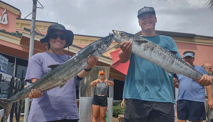 Couple with their catch on the Panama City Beach dock after a successful Saltshaker Charters fishing trip in Florida