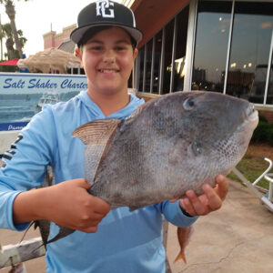 Boy with his catch on the Panama City Beach dock after a successful Saltshaker Charters fishing trip in Florida